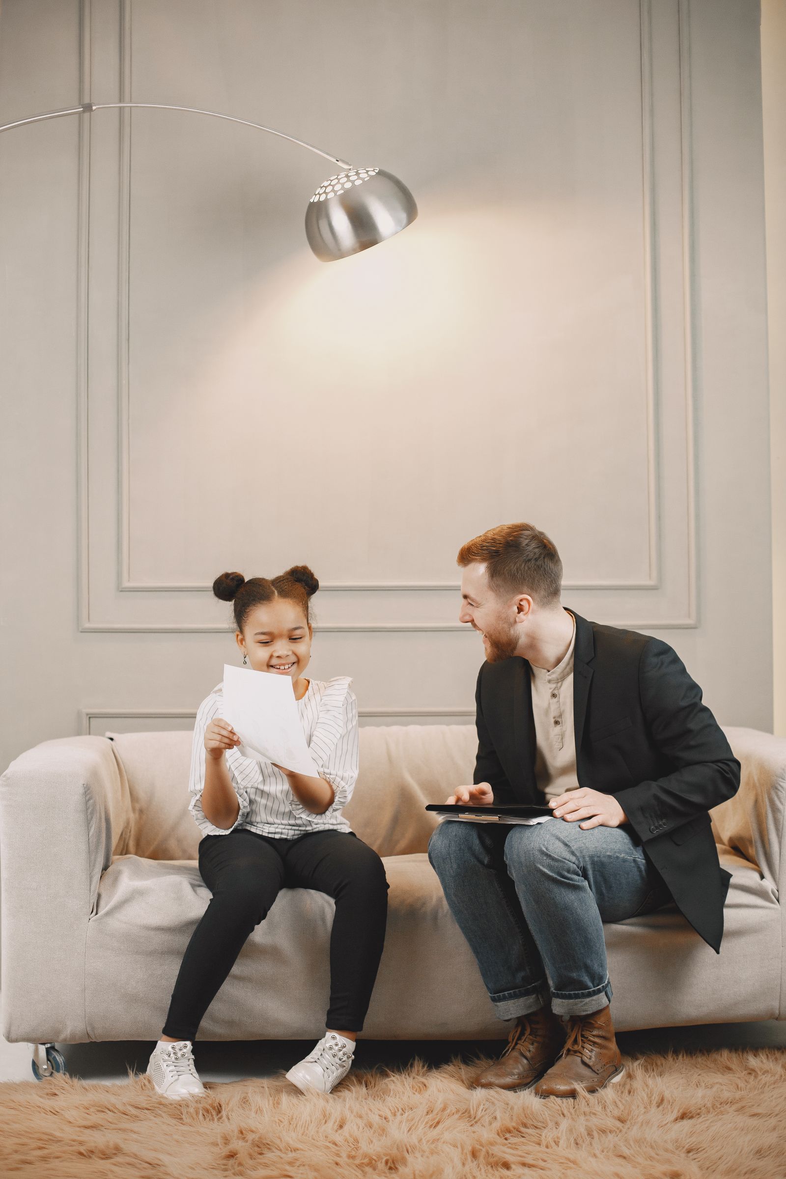 A smiling tutor working one-on-one with a young student at a table